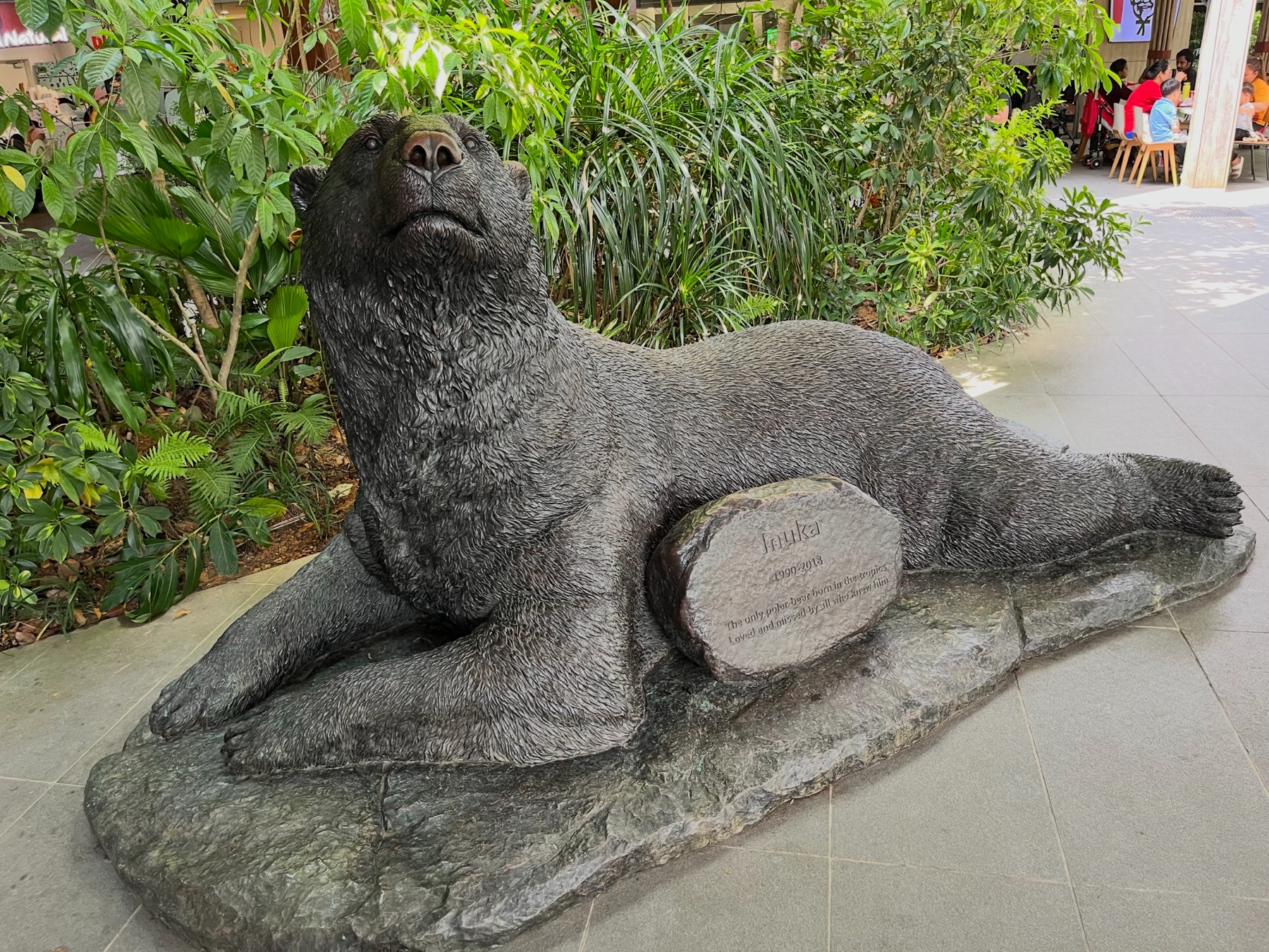 Bronze statue of Inuka the polar bear among tropical plants